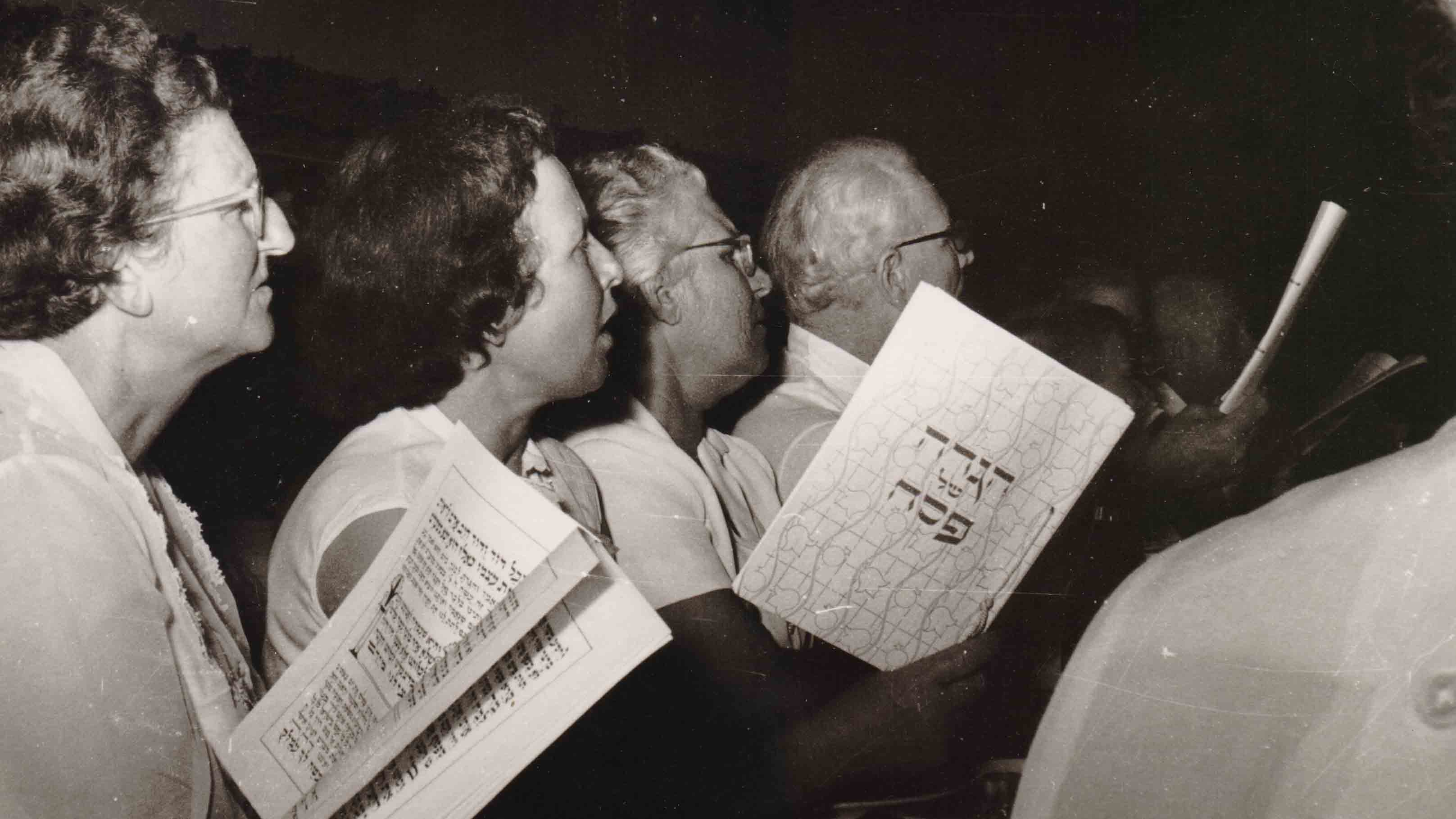 סדר פסח ביגור, 1962. המשתתפים קוראים בהגדת יגור מ-1958, אותה כתב ואייר שלמה קנטור (צילום: ארכיון קיבוץ יגור)