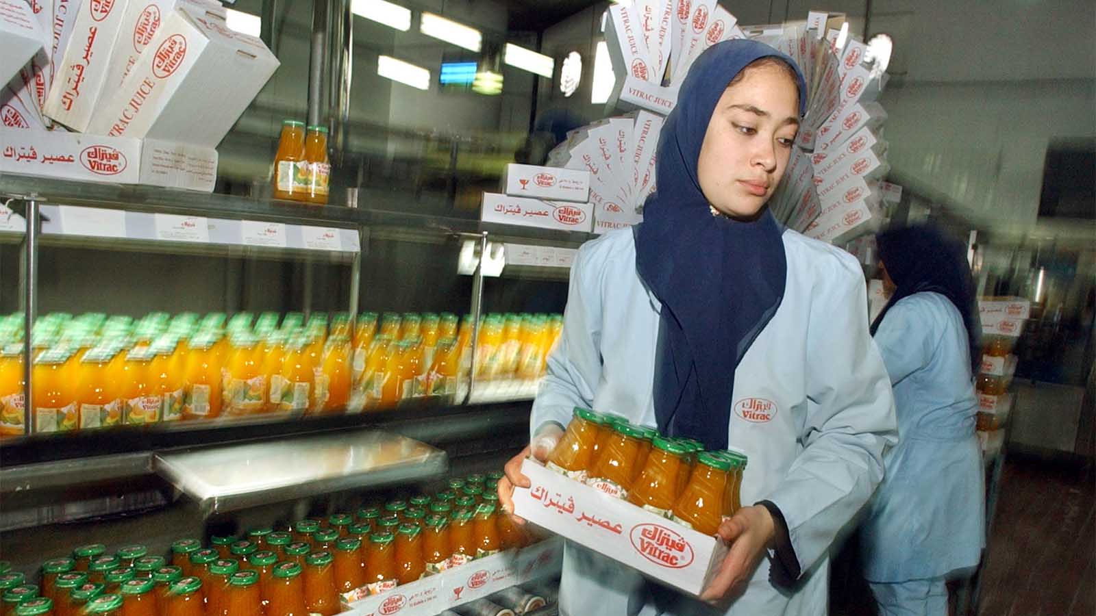 עובדת מצרית סוחבת ארגז מיצים במפעל בקהיר שנמצא באזור הסחר החופשי של מצרים וישראל. ארכיון 18 בדצמבר 2004 (AP Photo/Amr Nabil)