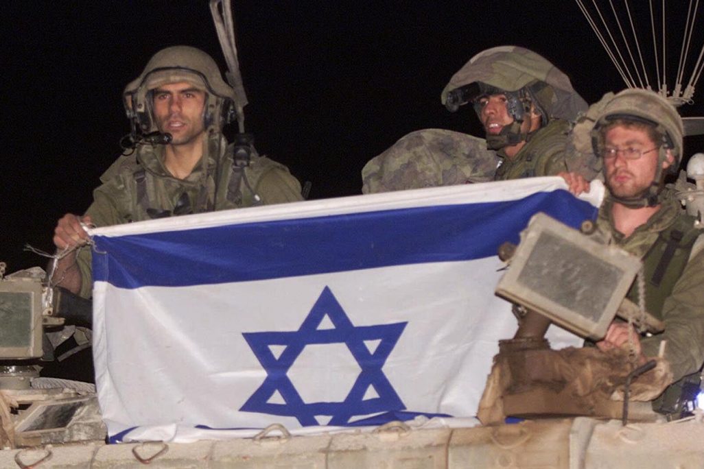 נסיגת צה"ל מרצועת הביטחון. חיילי צה"ל פורשים את דגל ישראל עם הכניסה חזרה לשטח מדינת ישראל  May 24, 2000. (AP Photo/Lefteris Pitarakis)