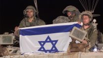 נסיגת צה"ל מרצועת הביטחון. חיילי צה"ל פורשים את דגל ישראל עם הכניסה חזרה לשטח מדינת ישראל  May 24, 2000. (AP Photo/Lefteris Pitarakis)