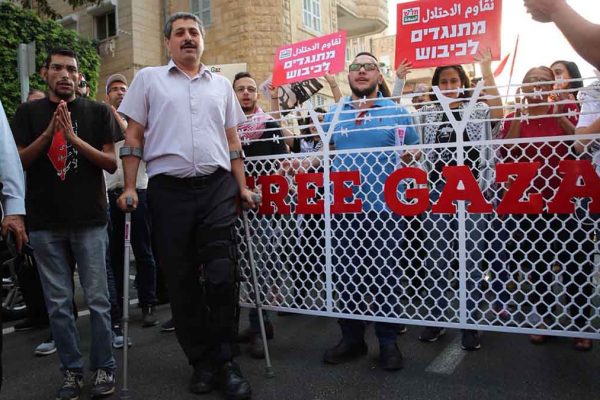 ג׳עפר פארח בהפגנה בחיפה לאחר מעצרו שמהלכו נשבר הברך שלו. 1 ביוני 2018 (צילום: זאהר אבו אלנסר)