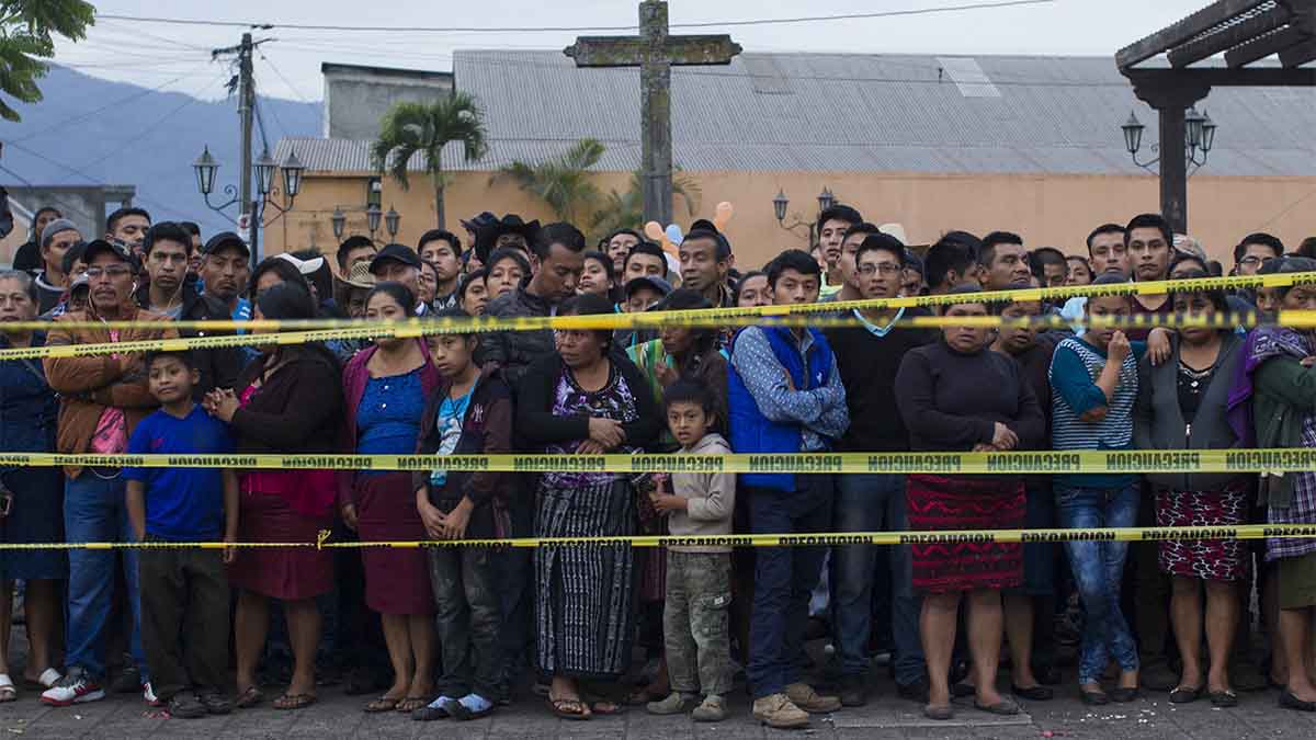 שכנים עומדים בסמוך למקום כינוס הגופות שאותרו על ידי כוחות ההצלה שהגיעו לאלוטננגו . (AP Photo/Luis Soto)