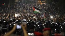Jordanian protesters shout slogans and raise a national flag during a demonstration outside the Prime Minister's office in the capital Amman early Monday, June 4, 2018.  Thousands of Jordanians protested against a planned tax increase for a fourth straight day Sunday, marching toward the office of the prime minister and demanding his resignation. (AP Photo/Raad Adayleh)