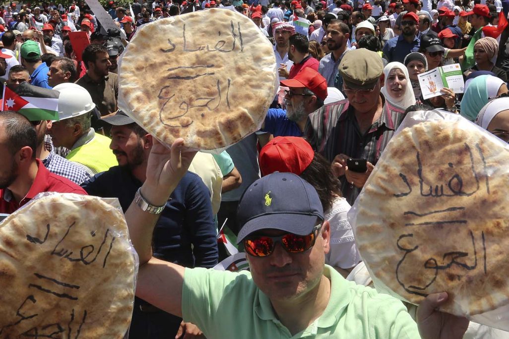 מפגינים בעמאן, מניפים פיתות עם הכיתוב "שחיתות שווה רעב" (צילום: (AP Photo/Raad al-Adayleh).