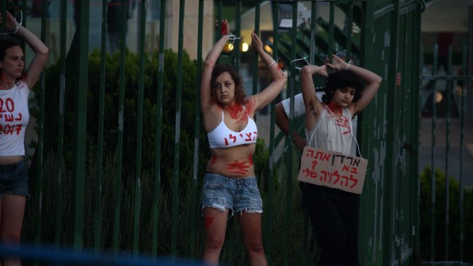 פעילות שקשרו עצמן לגדר של הכנסת במחאה על רציחות נשים, 13 ביוני 2018. (צילום: מרטין קיאל).