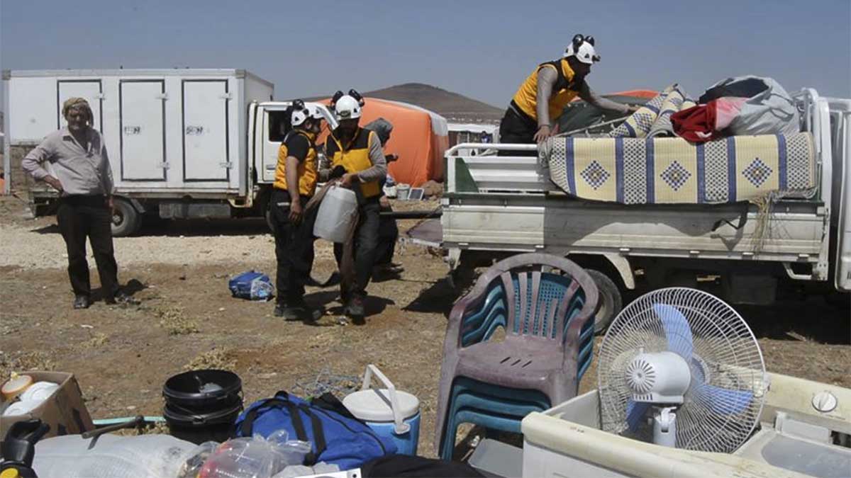 אנשי ארגון הקסדות הלבנות מסייעים לפליטים מדרעא להתמקם בעיירה קונטרה סמוך לגבול עם ישראל. 28 ביוני (Syrian Civil Defense White Helmets via AP)