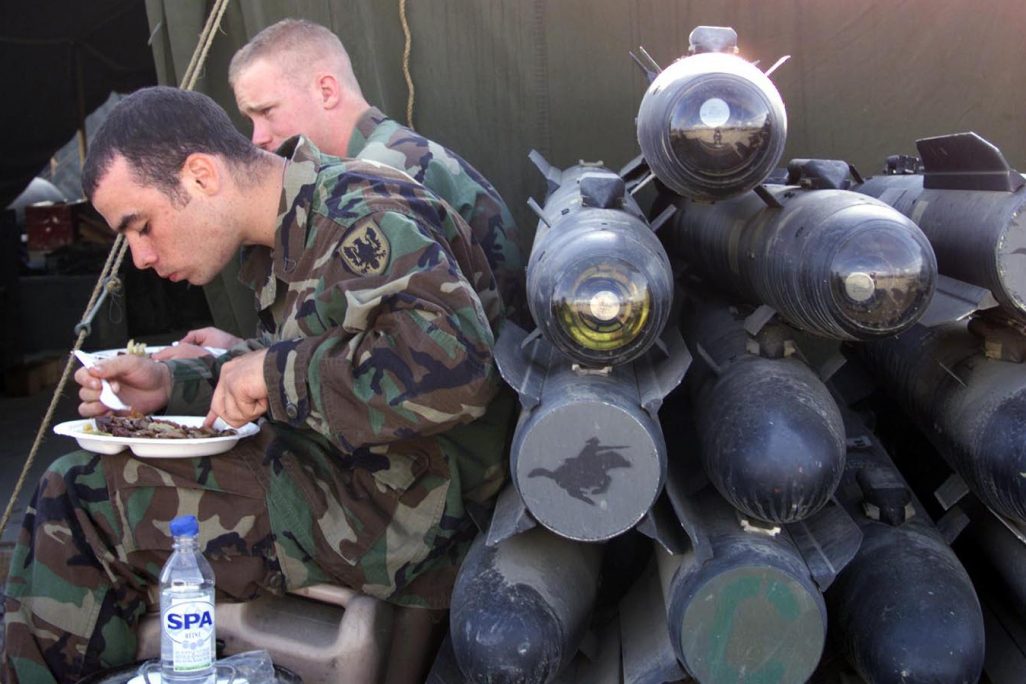 חיילים אמריקאים אוכלים לצד ערימת טילים מסוג Hellfire (צילום: AP Photo/Darko Bandic).