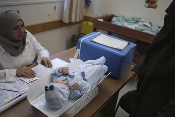 אשה פלסטינית ותינוקה בבדיקה במרפאת אונר"א במחנה הפליטים שאטה הסמוך לעזה, 14 בינואר 2018. (AP Photo/ Khalil Hamra)