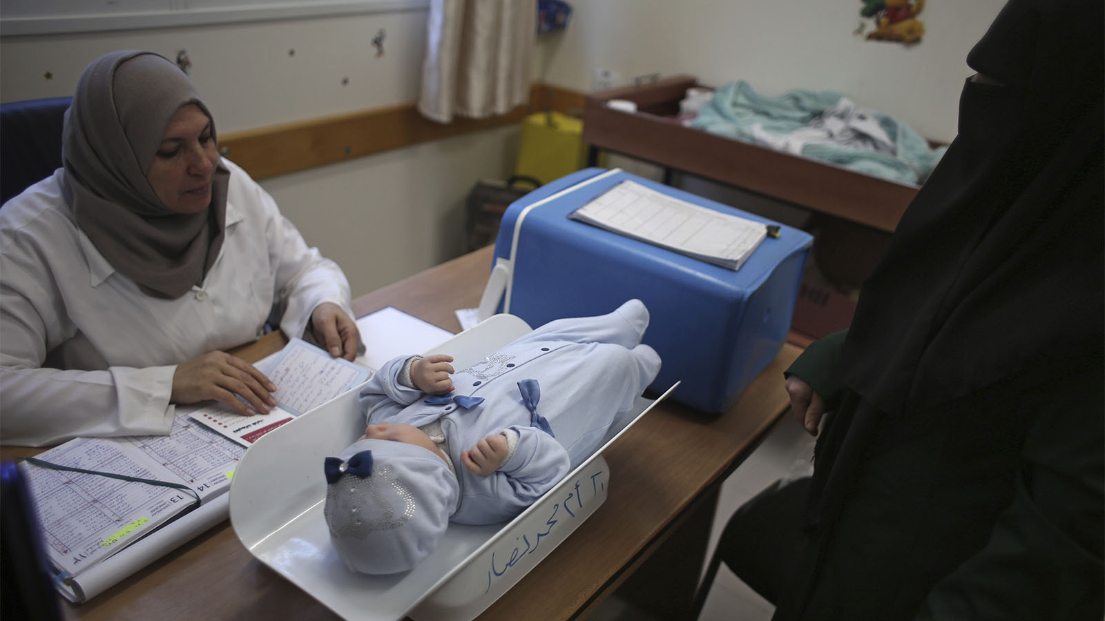 אשה פלסטינית ותינוקה בבדיקה במרפאת אונר&quot;א במחנה הפליטים שאטה הסמוך לעזה, 14 בינואר 2018. (AP Photo/ Khalil Hamra)