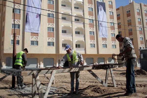 פלסטינים עובדים בבניית פרוייקט הדיור "חמד סיטי" בחאן יונס שבדרום רצועת עזה, הממומן ע"י קטאר, 16 בינואר 2016. (AP Photo/ Khalil Hamra)