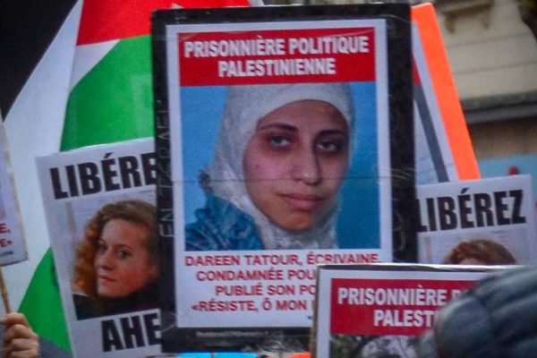 שלט מחאה הנושא את תמונתה של דארין טאטור בהפגנה בצרפת (צילום: Jeanne Menjoulet / Flickr).