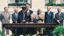 טקס החתימה על הסכמי אוסלו, בין ישראל לפלשתינאים, בבית הלבן בוושינגטון. בצילום, שר החוץ שמעון פרס חותם עם ההסכם. מאחור (משמאל לימין), שר החוץ הרוסי אנדריי קוזירי, ראש הממשלה יצחק רבין, נשיא ארה"ב ביל קלינטון, יו"ר אש"ף יאסר ערפאת, מזכיר המדינה האמריקאי וורן כריסטופר ואבו מאזן. (צילום: אבי אוחיון / לע"מ).