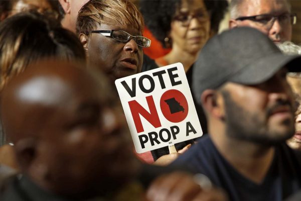 מפגינים נושאים שלט הקורא להתנגד לחוק "הזכות לעבוד" במשאל העם במיזורי (AP Photo/Charlie Riedel)