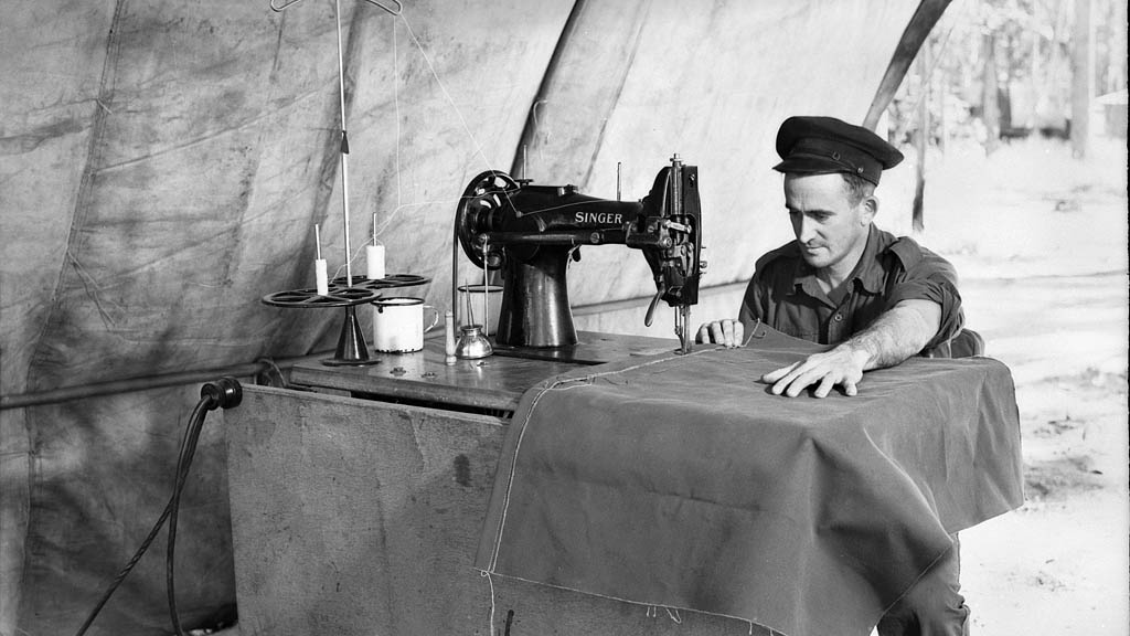 איש צבא אוסטרלי משתמש במכונת תפירה של זינגר לתפור תיקי קנבס במלחמת העולם השנייה. (צילום: Australian War Memorial collection/ Flicker)