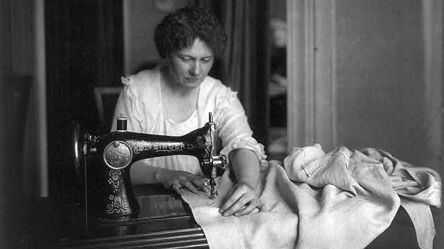 אישה תופרת בביתה עם מכונת תפירה של זינגר (צילום: Library of Congress/ ויקימדיה)