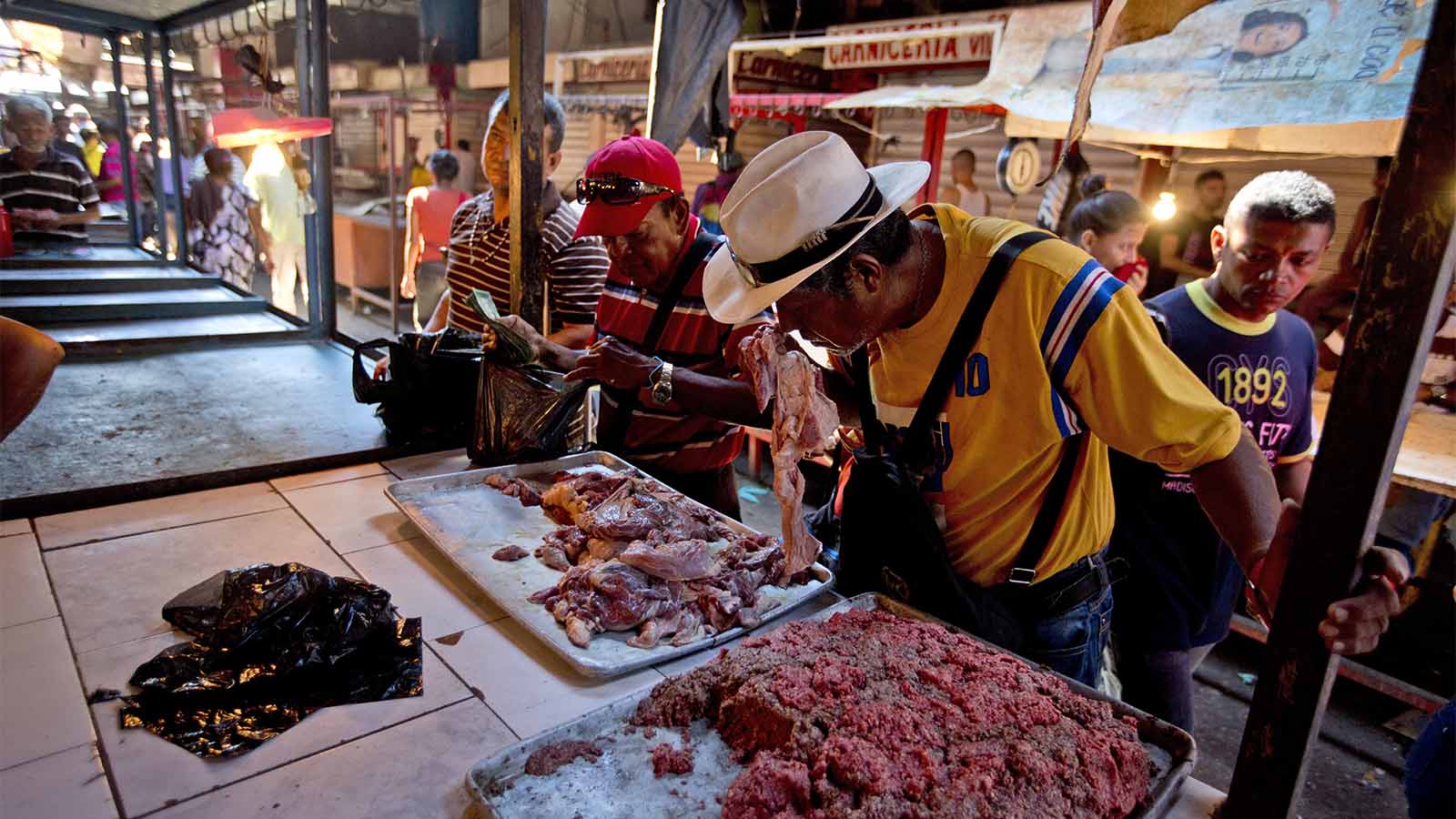 קונה מריח חתיכת בשר מקולקל בשוק בוונצואלה (AP Photo/Fernando Llano)