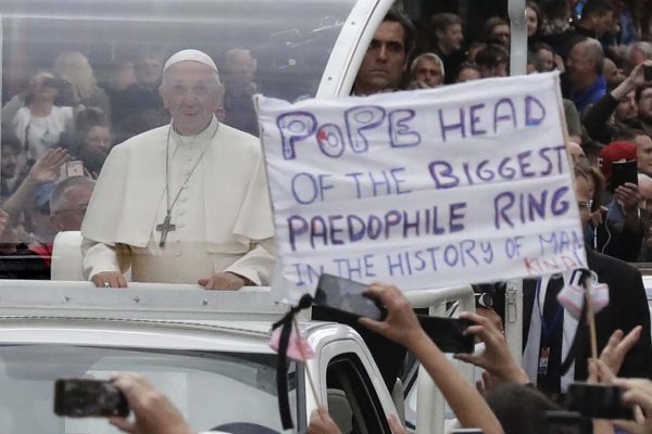 האפיפיור פראנסיס עובר יד שלט של מפגין בביקור באירלנד (צילום: AP Photo/Matt Dunham).