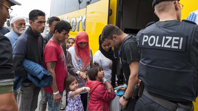 מהגרים עולים על אוטובוס בפסאו שבגרמניה, בנקודת קליטה של פליטים ומהגרים (צילום: shutterstock).