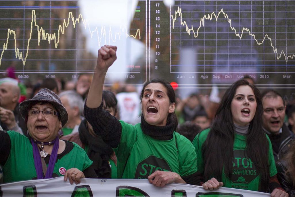 מחאה נגד פינויי בתים לצד מראה הגרפים בבורסת המניות בספרד לאחר משבר 2009 (צילום: AP photo).