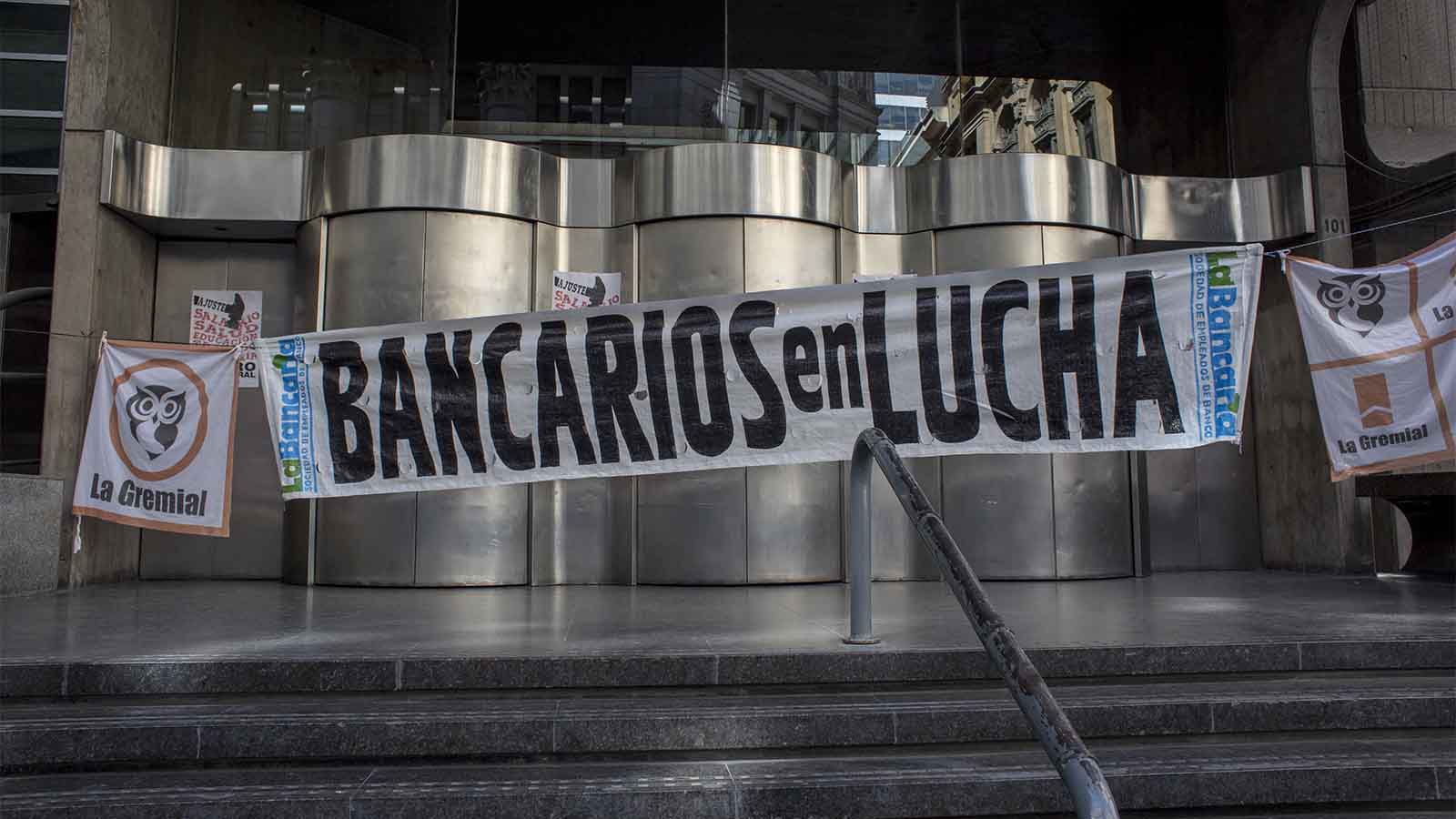 שלט בו כתוב &quot;עובדי הבנק מצטרפים למאבק&quot; בכניסה לסניף הסגור לרגל שביתה כללית שהוכרזה בארגנטינה ב-25 לספטמבר 2018 Sarah Pabst/Bloomberg via Getty Images