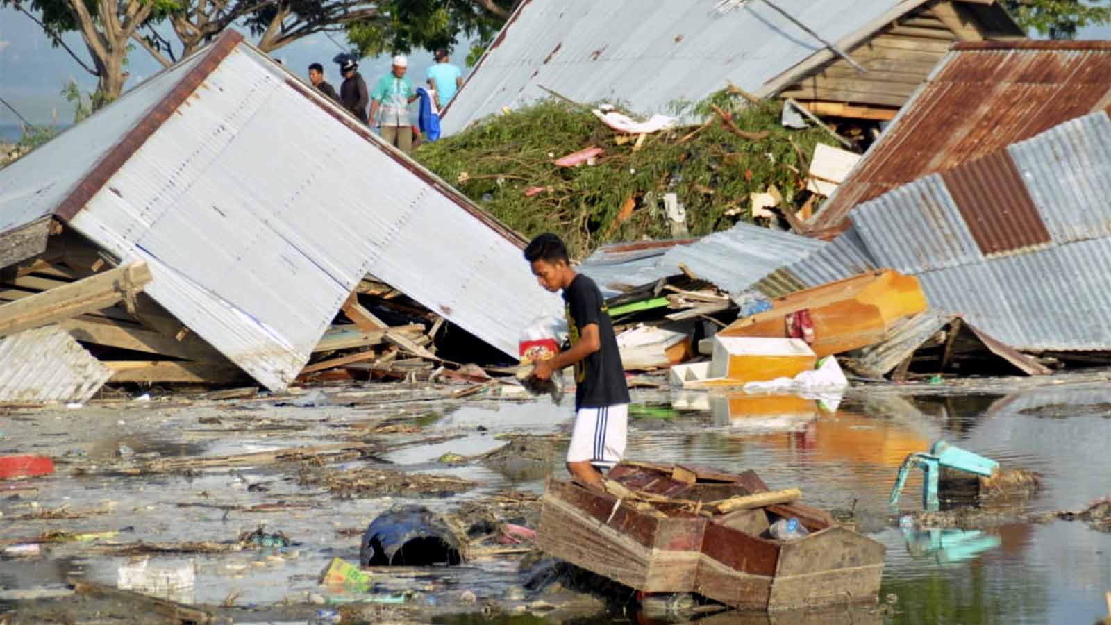 אדם בהריסות ביתו כתוצאה מרעידת אדמה וצונאמי בפאלו, אינדונזיה. 29 בספטמבר 2018. (AP Photo/Rifki)