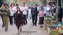 יהודים מסיירים בשוק בחברון יחד עם אבטחה של חיילי צה"ל (צילום: נג'ה השלמון / פלאש 90).