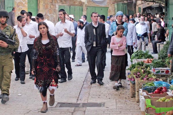 יהודים מסיירים בשוק בחברון יחד עם אבטחה של חיילי צה"ל (צילום: נג'ה השלמון / פלאש 90).