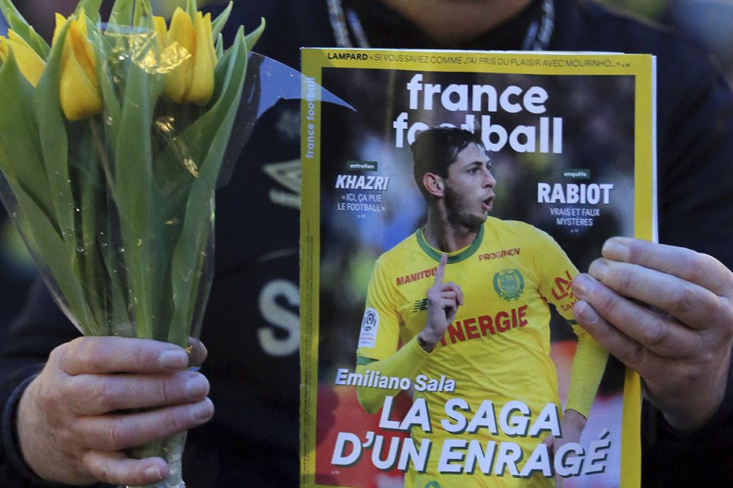 אוהד כדורגל מחזיק מגזין צרפתי עם תמונת שער של אמיליאנו סאלה, בהתאספות לזכרו של אוהדי כדורגל בצרפת (צילום: AP Photo/David Vincent).