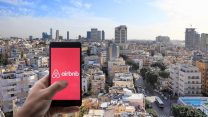 אפליקציית Airbnb ברקע העיר תל אביב (צילום: Shutterstock)
