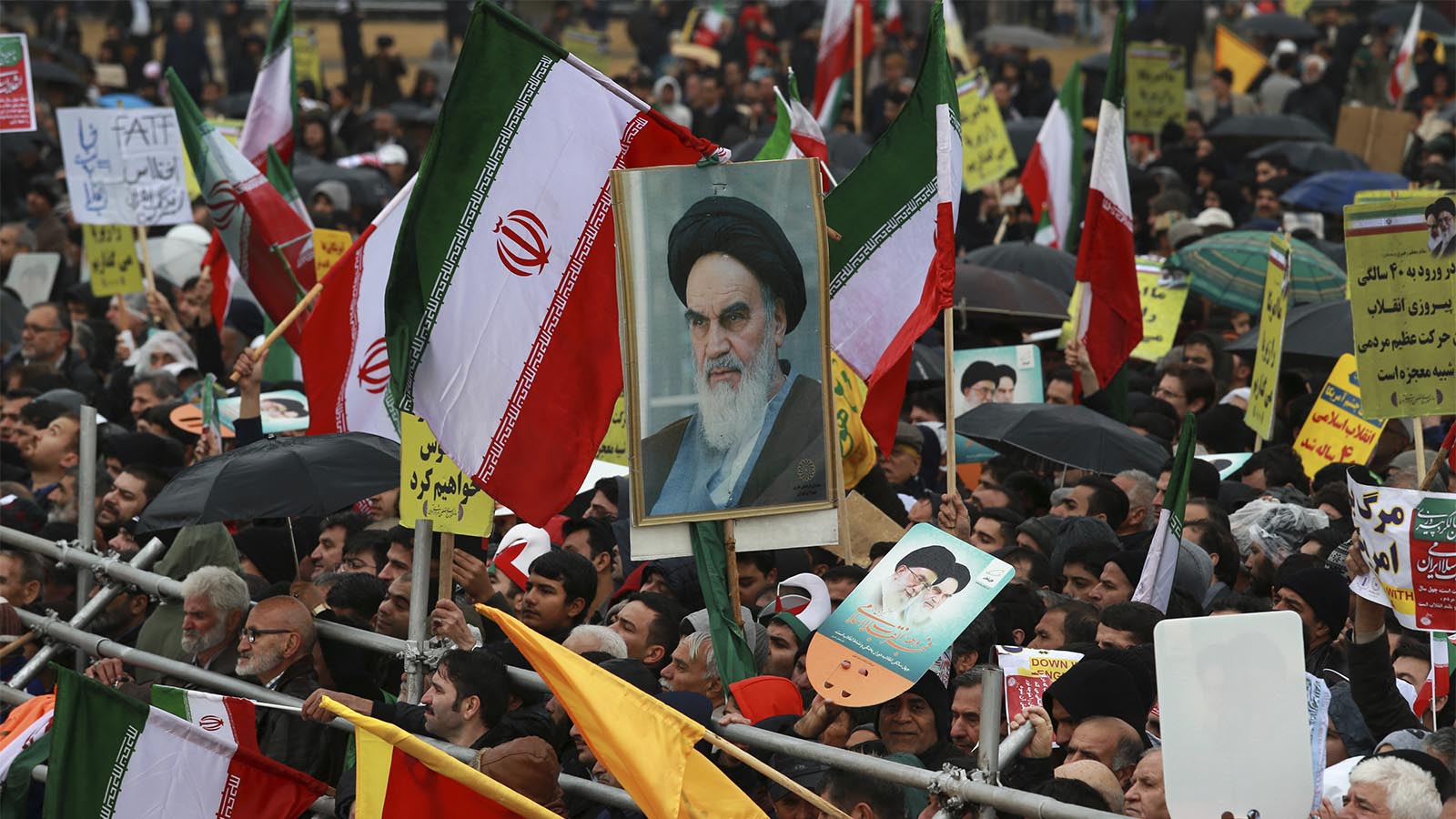 אזרחי איראן בטקס חגיגת 40 שנה למהפכה האסלמית באיראן. מאות אלפי אנשים הציפו את רחובות טהראן והתכנסו סביב כיכר החרות בעיר. אחד המפגינים נושא תמונת ענק של חומייני, המנהיג העליון הראשון של איראן . (AP Photo/Vahid Salemi)