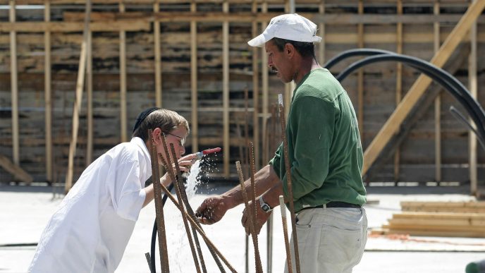 פועל בניין פלסטיני ונער חרדי שותים מברז מים באתר בנייה ברמת שלמה, ירושלים (צילום: קובי גדעון / פלאש 90).