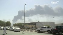 In this image made from a video broadcast on the Saudi-owned Al-Arabiya satellite news channel on Saturday, Sept. 14, 2019, a man walks through a parking lot as the smoke from a fire at the Abqaiq oil processing facility can be seen behind him in Buqyaq, Saudi Arabia. Drones launched by Yemen's Houthi rebels attacked the world's largest oil processing facility in Saudi Arabia and another major oilfield Saturday, sparking huge fires at a vulnerable chokepoint for global energy supplies. (Al-Arabiya via AP) TV OUT NO SALES