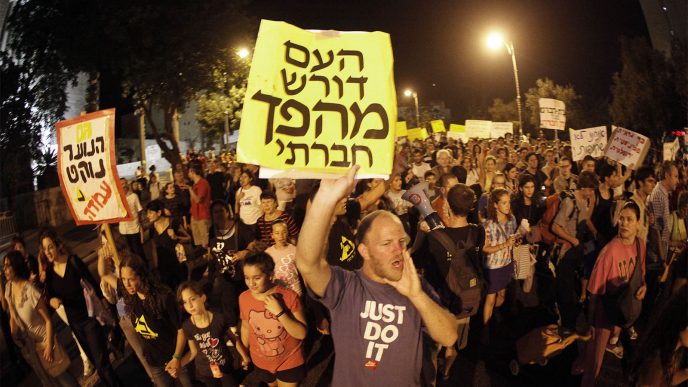 A protest in Jerusalem in 2011. A man holds a sign reading “the nation demands a social revolution.” (Photo: Ori Lantz / Flash90)