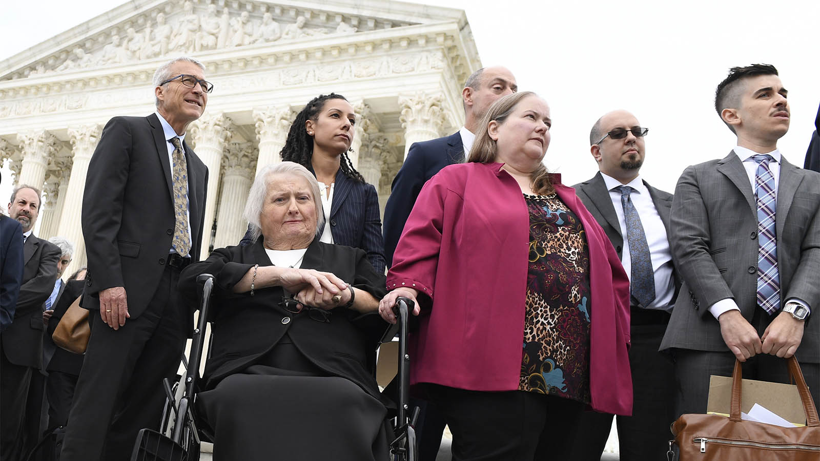 איימי סטפנס (בכסא) אישתה דונה ועורך הדין שלה (מימין) בכניסה לדיון בבית המשפט העליון של ארה&quot;ב בנושא פיטוריה בשל היותה טרנסית. 8 באוקטובר 2019 (AP Photo/Susan Walsh)