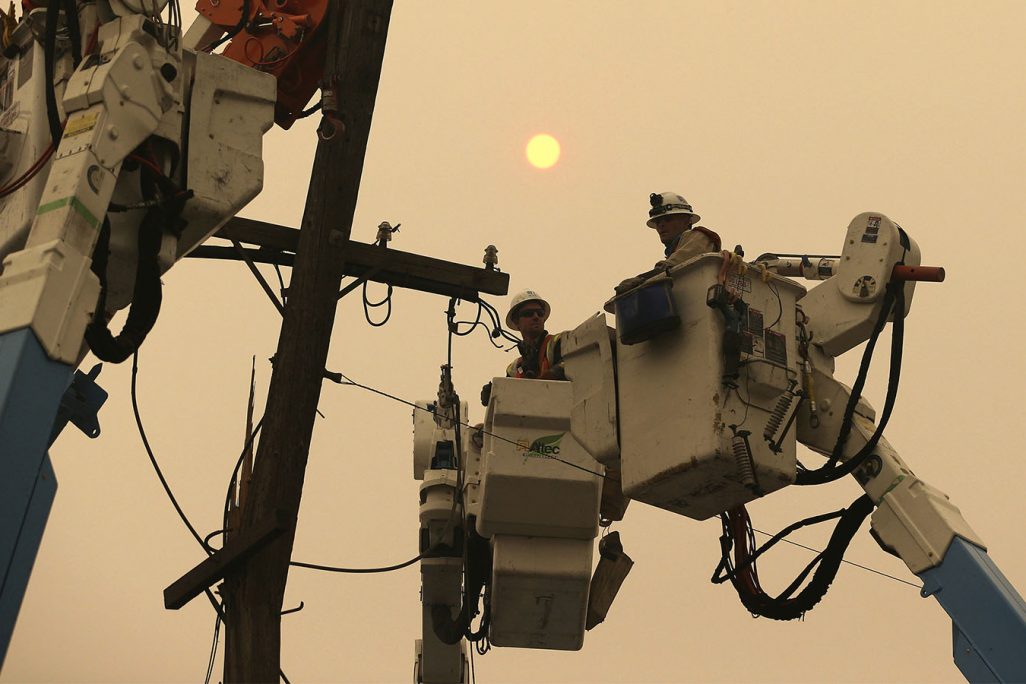 צוותי חברת החשמל הפרטית PG&E מתקנים קווי חשמל לאחר השריפה שכילתה את העיר פרדייז במדינת קליפורניה בארה"ב, 9 בנובמבר 2018. (AP Photo/Rich Pedroncelli, File)