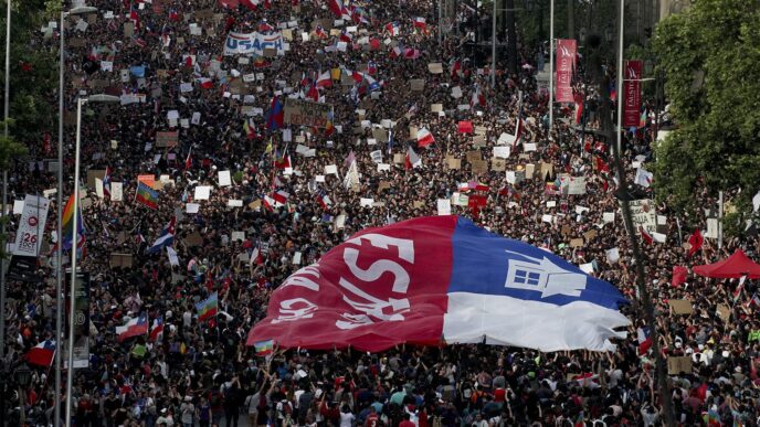 מפגינים צ'ילאנים מניפים דגל ענק מהלך מחאות ברחבי צ'ילה. 25 באוקטובר 2019 (AP Photo/Esteban Felix)