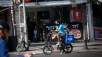 שליח וולט בתל אביב, ממתין לאיסוף משלוח מחוץ למסעדה (מרים אלסטר/פלאש90)