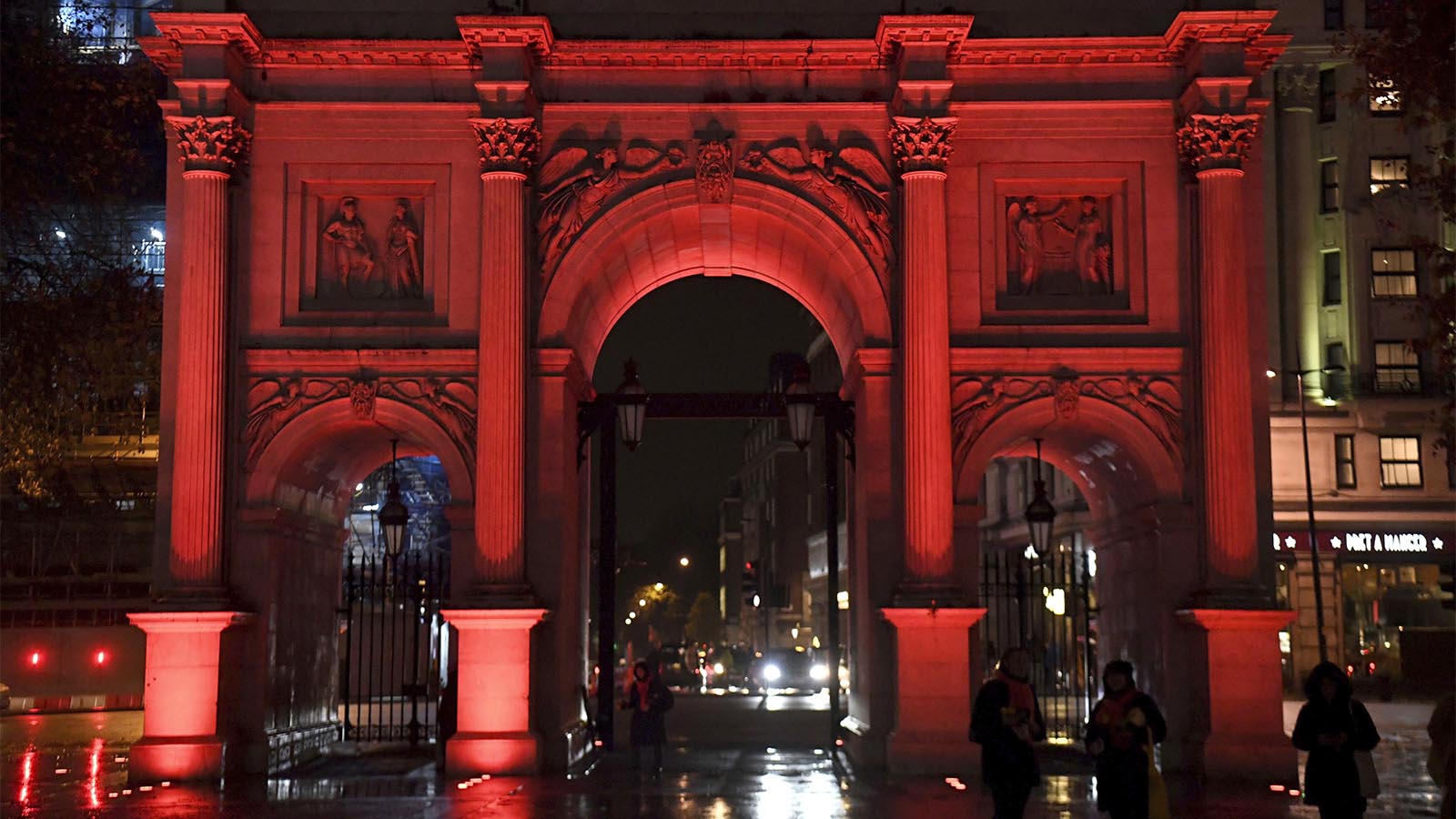 מרבל ארץ' בלונדון מוארת במחאה על האלימות כנגד נשים. ברחבי העולם אתרים מרכזיים הוארו במנורות בצבע אדום כחלק מיום המאבק הבינלאומי (Kirsty O'Connor/PA via AP)