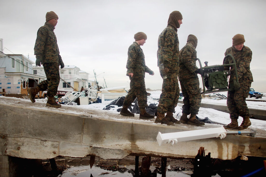 חיילי ה'מארינס' מגדוד 8 של התמיכה ההנדסית בצבא ארה"ב מחוץ למחנה ליון סוחבים גנרטור שבו ישתמשו לשאיבת מים באיזור נוראיסטר, שנפגע בהוריקן 'סנדי', 8 בנובמבר 2012 (Photo by Mario Tama/Getty Images)