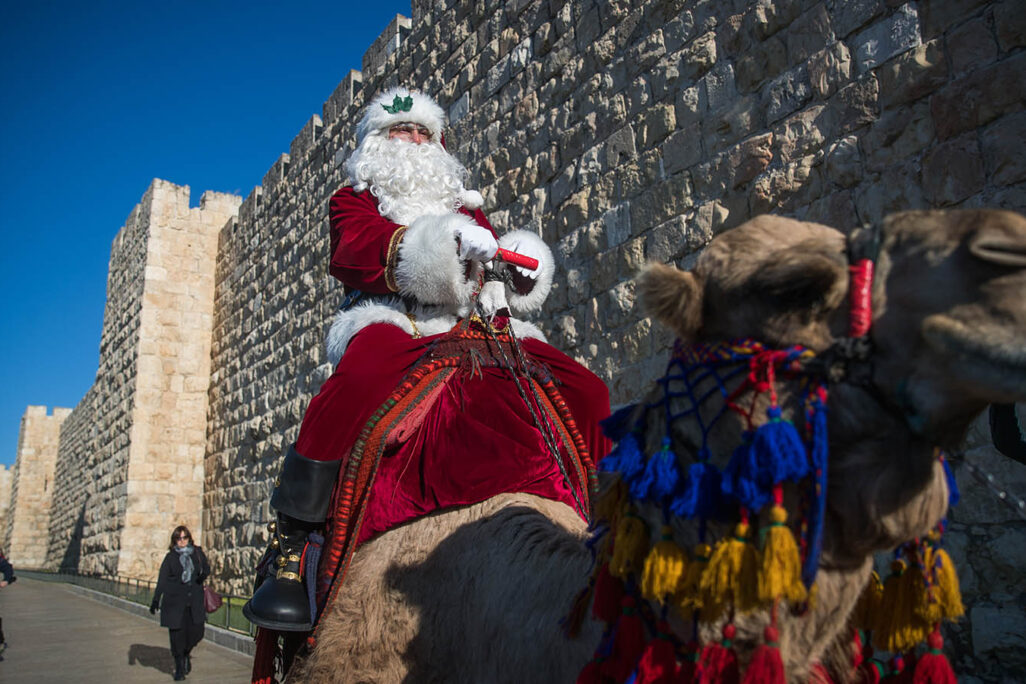 עיסה קסיסייה לבוש כסנטה קלאוס רוכב על גמל מחוץ לשער יפו בעיר העתיקה בירושלים (צילום: יונתן זינדל/פלאש90)