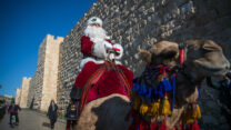 עיסה קסיסייה לבוש כסנטה קלאוס רוכב על גמל מחוץ לשער יפו בעיר העתיקה בירושלים (צילום: יונתן זינדל/פלאש90)