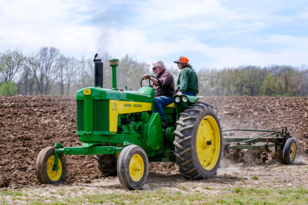 חקלאים בארצות הברית משתמשים בטרקטור ישן של חברת ג'ון דיר (iyd39 / Shutterstock.com)