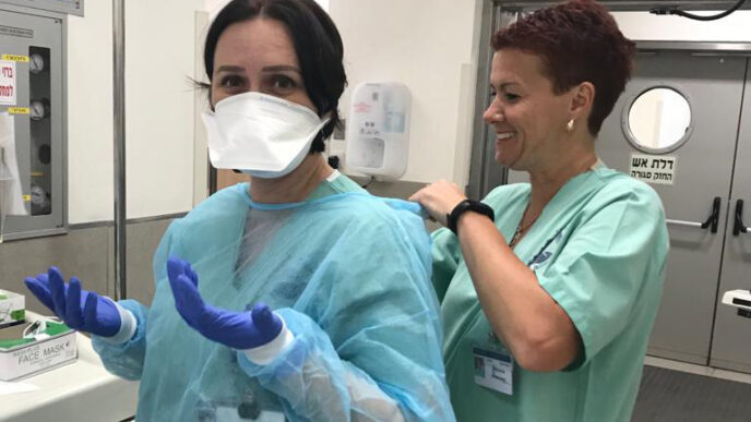 الممرضات كاتي زاك وأولغا ميريك يضعن الحماية الذاتية  قبل وصول مريض مشتبه مصاب بالفيروس الجديد. (تصوير: مستشفى بوريا)