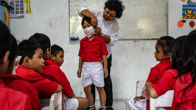 גננת מלמדת את ילדי הגן כיצד ללבוש מסכה נגד קורונה. ג'אקרטה אינדונזיה (Photo by Ulet Ifansasti/Getty Images)