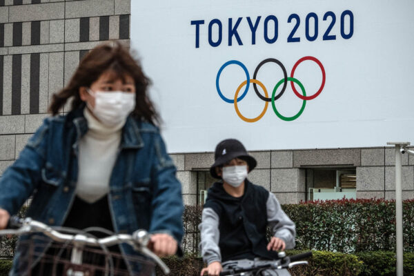 אנשים ביפן על רקע סמל אולימפיאדת טוקיו 2020, 13 במרץ 2020 (Photo by Carl Court/Getty Images)