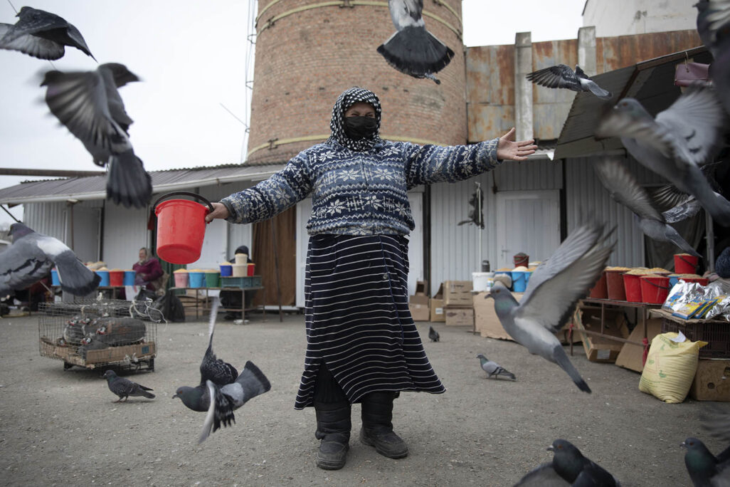 امرأة مع قناع ضد الكورونا تطعم الحمام في سوق في غروزني بالشيشان. 24 مارس (Photo by Yelena Afonina\TASS via Getty Images)