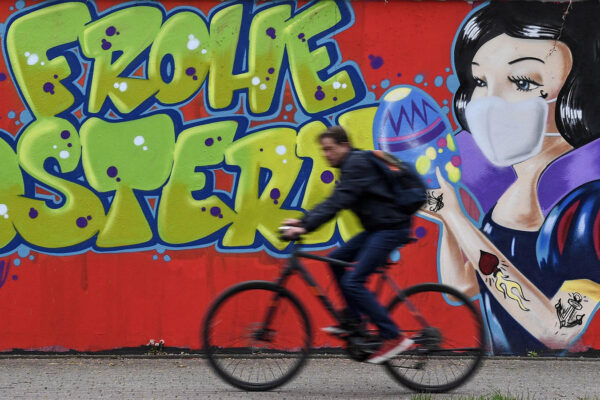 רוכב אופניים בעיר האם בגרמניה. 13 באפריל. בגרפיטי ברקע רשום 'חג פסחא שמח' (AP Photo/Martin Meissner)
