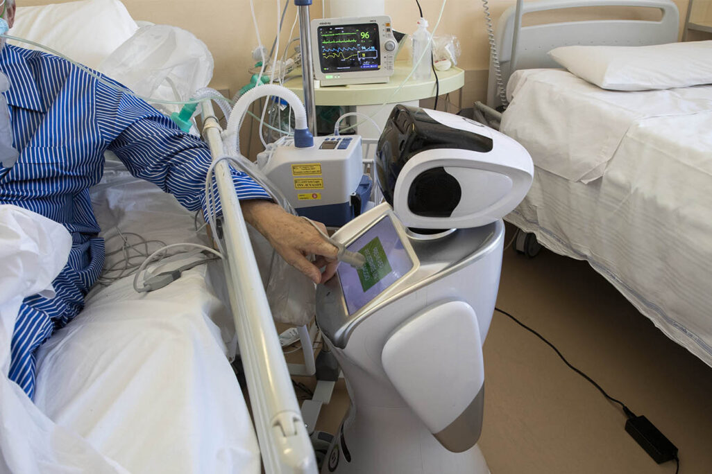 A coronavirus patient undergoing treatment in the ICU uses the touchscreen of a robot at 'Ospedale di Circolo' hospital, in Varese, Italy, Wed., April 8, 2020. (AP Photo/Luca Bruno)