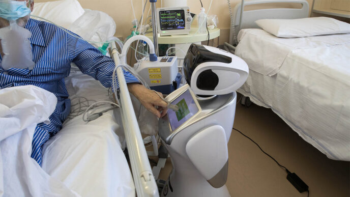 A coronavirus patient undergoing treatment in the ICU uses the touchscreen of a robot at 'Ospedale di Circolo' hospital, in Varese, Italy, Wed., April 8, 2020. (AP Photo/Luca Bruno)