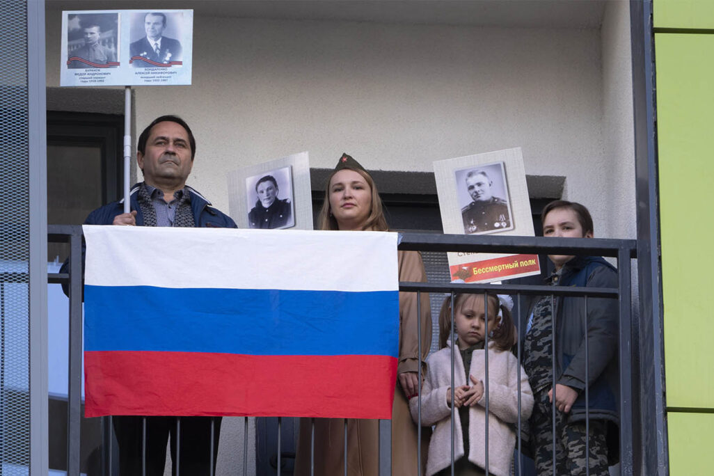 משפחה בסנט פטרסבורג עומדת במרפסת עם תמונות של קרובי משפחה וטרנים ביום הניצחון על גרמניה הנאצית. 9 במאי (AP Photo/Dmitri Lovetsky)